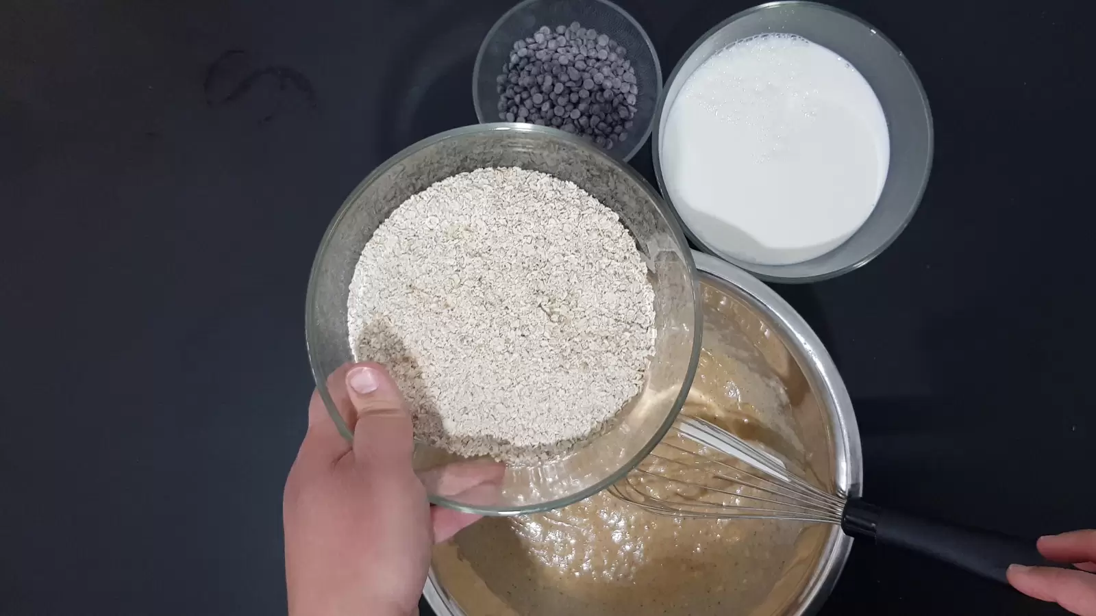 Bowl with chocolate chips, bowl with oats, bowl with milk, whisk, mix in a bowl