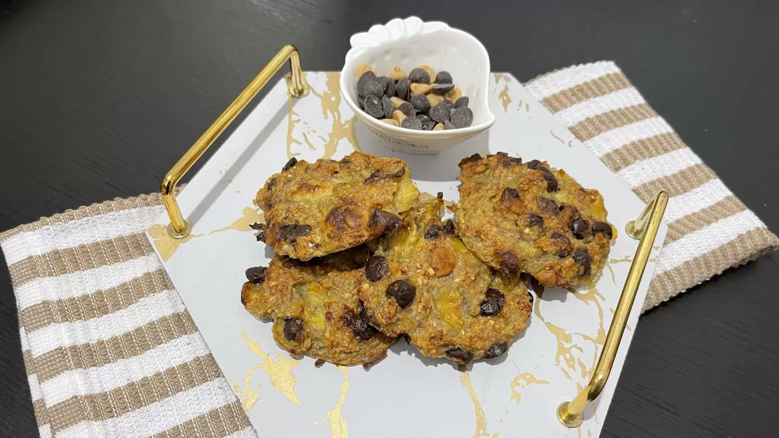 Banana and oatmeal cookies on a tray a bowl of chocolate chips on the table