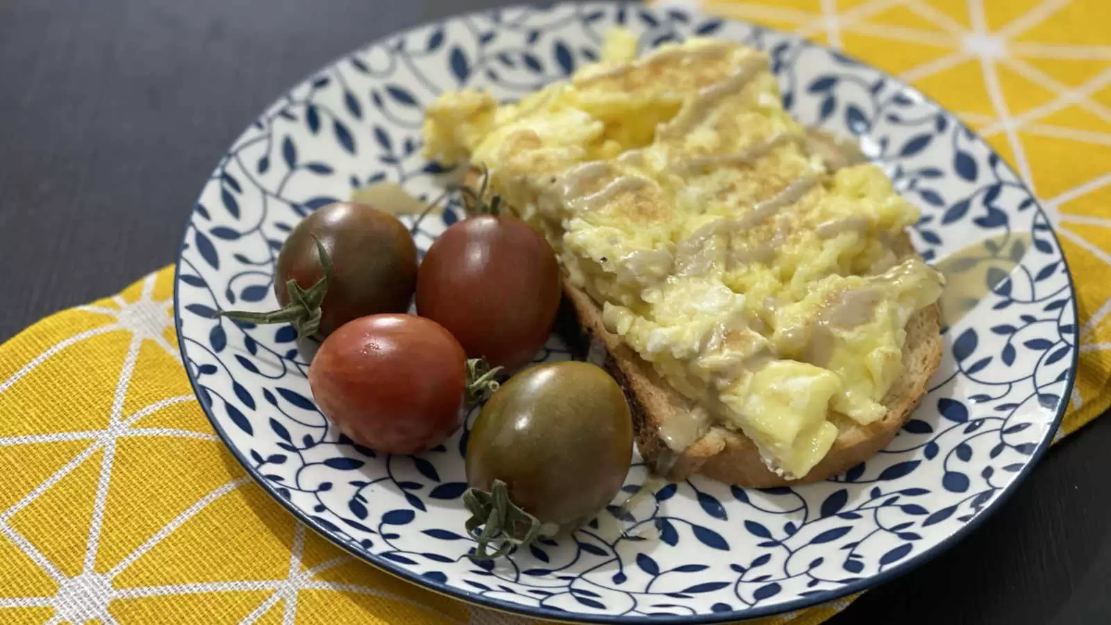 A basic omelette on a slice of bread next to tomatoes placed on a plate