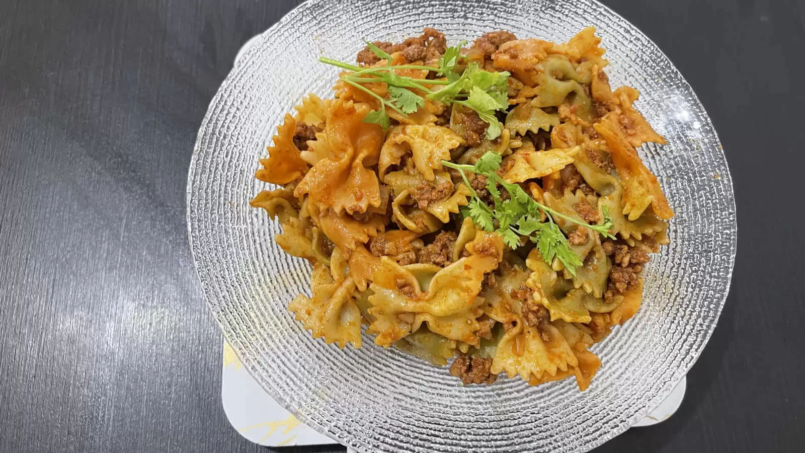 Farfalle with Bolognese on a plate on a black background