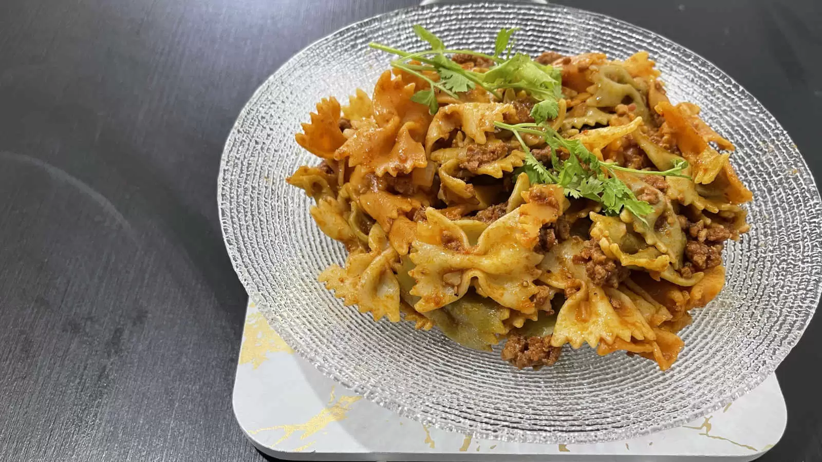 Farfalle with Bolognese dish on a plate on a black background