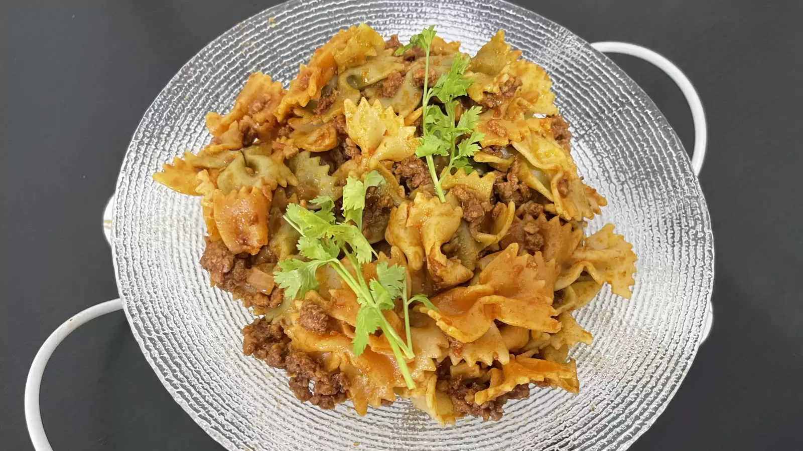 Recipe Farfalle with Bolognese on a plate on a black background