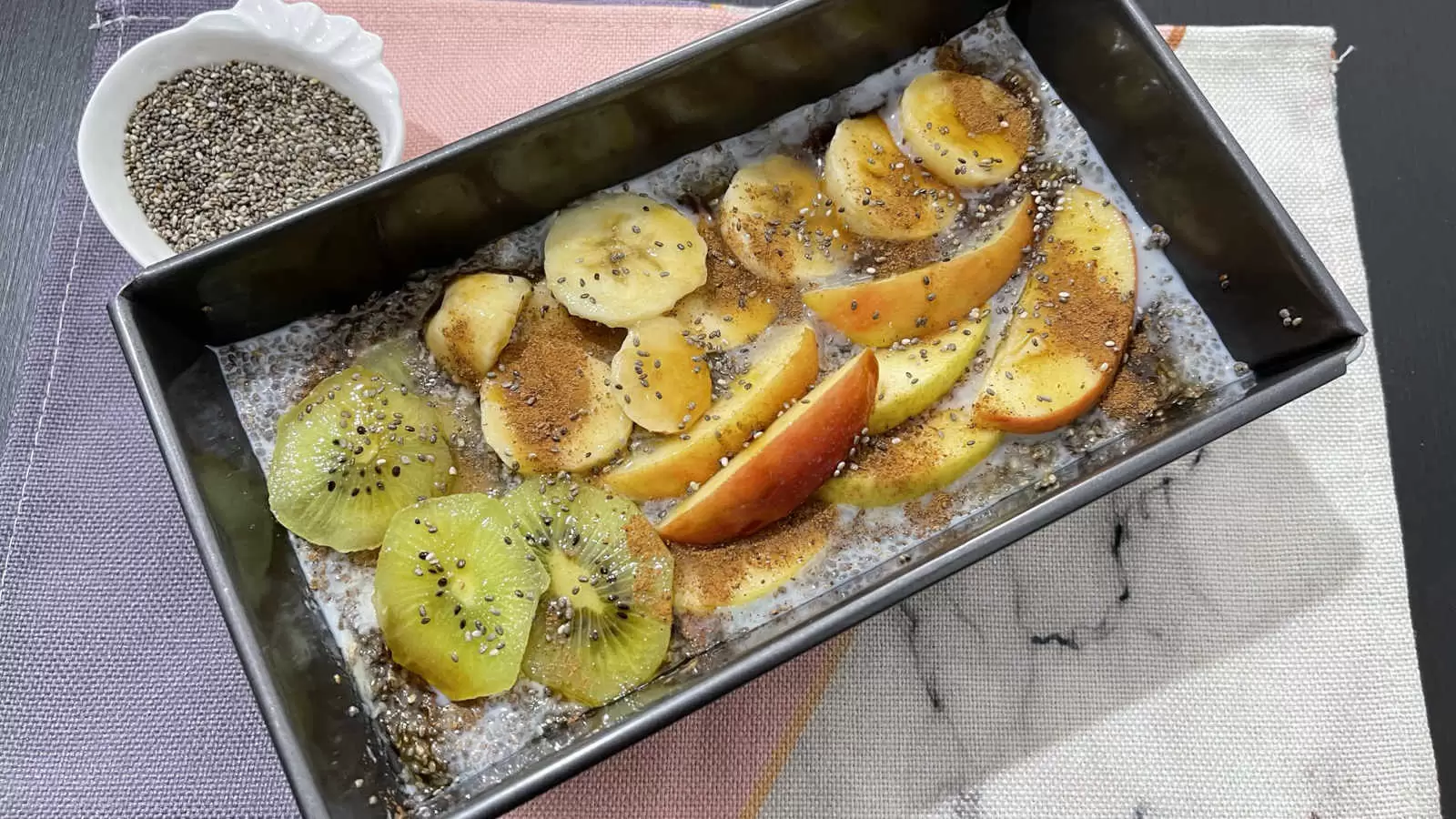 Chia pudding in a mold apple banana and cut kiwi bowl with chia seeds napkin underneath