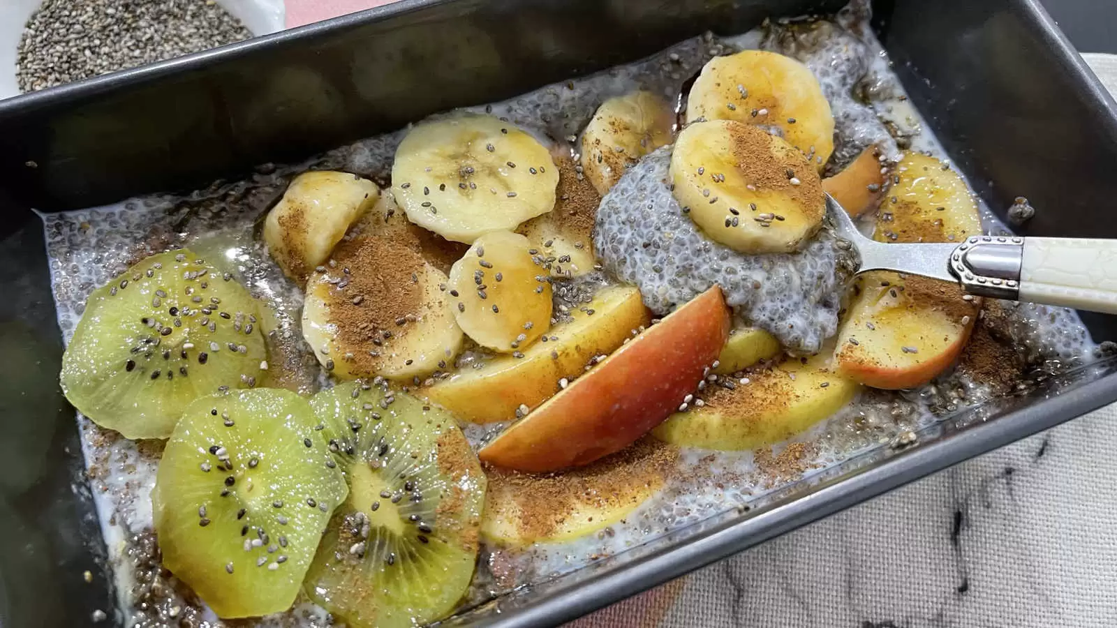 Chia pudding for breakfast in a mold tablespoon apple banana and cut kiwi bowl with chia seeds napkin underneathn