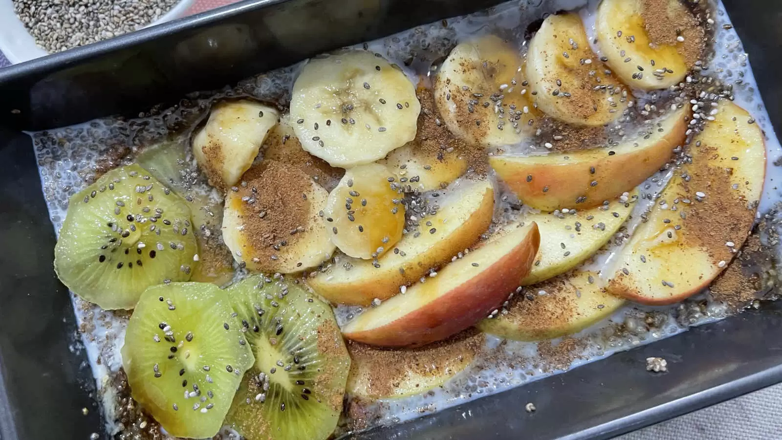 Chia pudding recipe in a mold apple banana and cut kiwi bowl with chia seeds napkin underneath