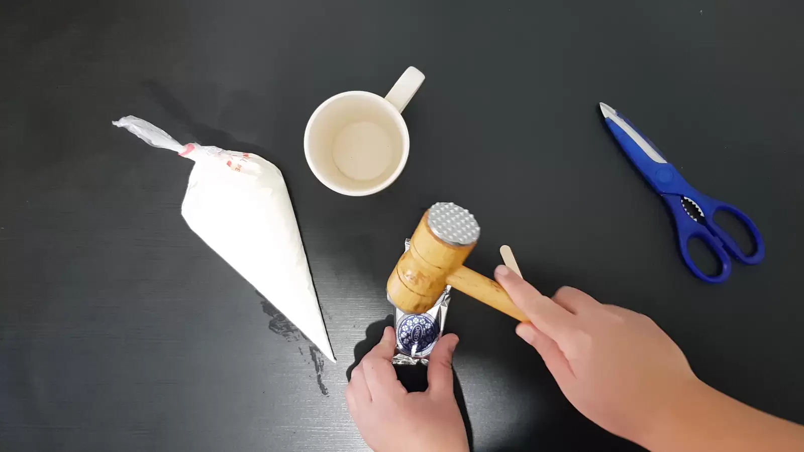 Scissors, kitchen hammer, package of Oreo cookies, cup, piping bag with whipped cream