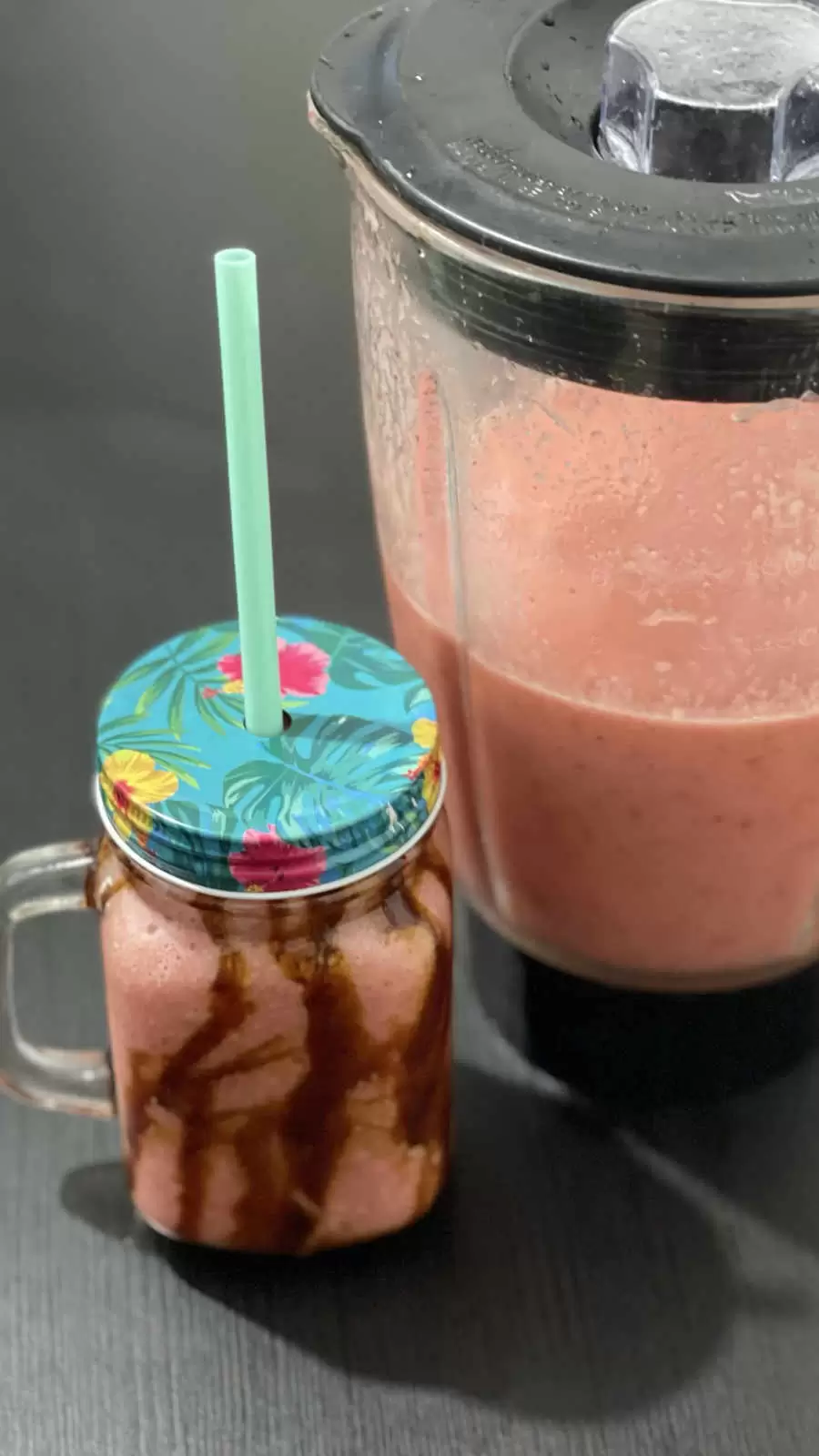 Apple banana and strawberry fruit smoothie in a glass and a blender