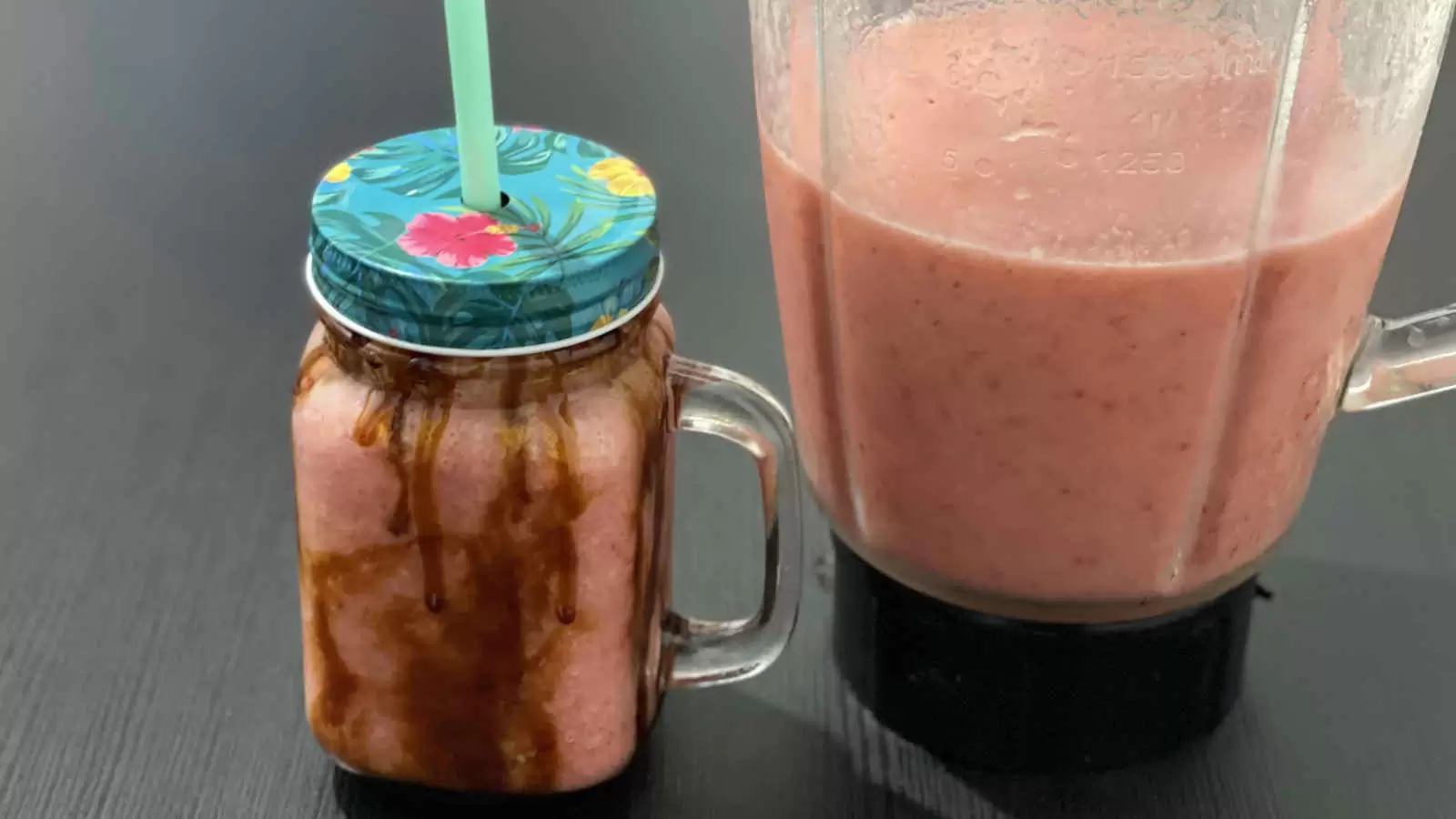 Apple banana and strawberry fruit smoothie in a glass and a blender