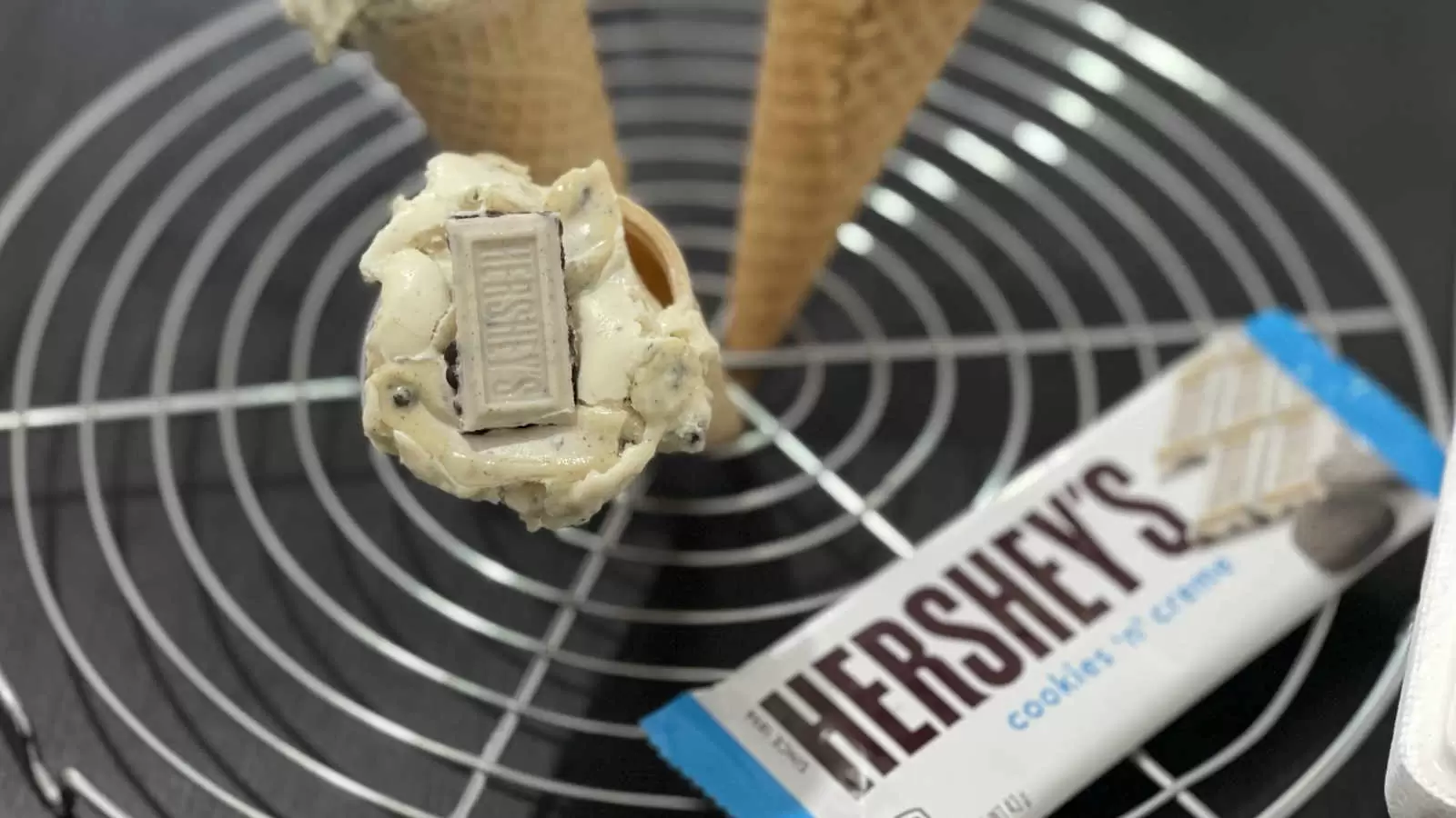 A cooling rack with three ice cream cones a pack of Hersheys chocolate dessert