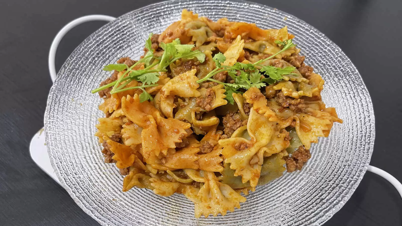 Homemade Farfalle with Bolognese on a plate on a black background