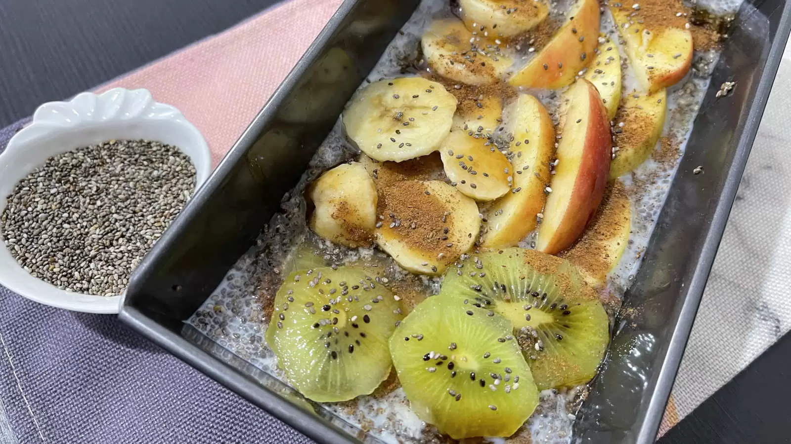 Homemade Chia pudding in a mold apple banana and cut kiwi bowl with chia seeds napkin underneath