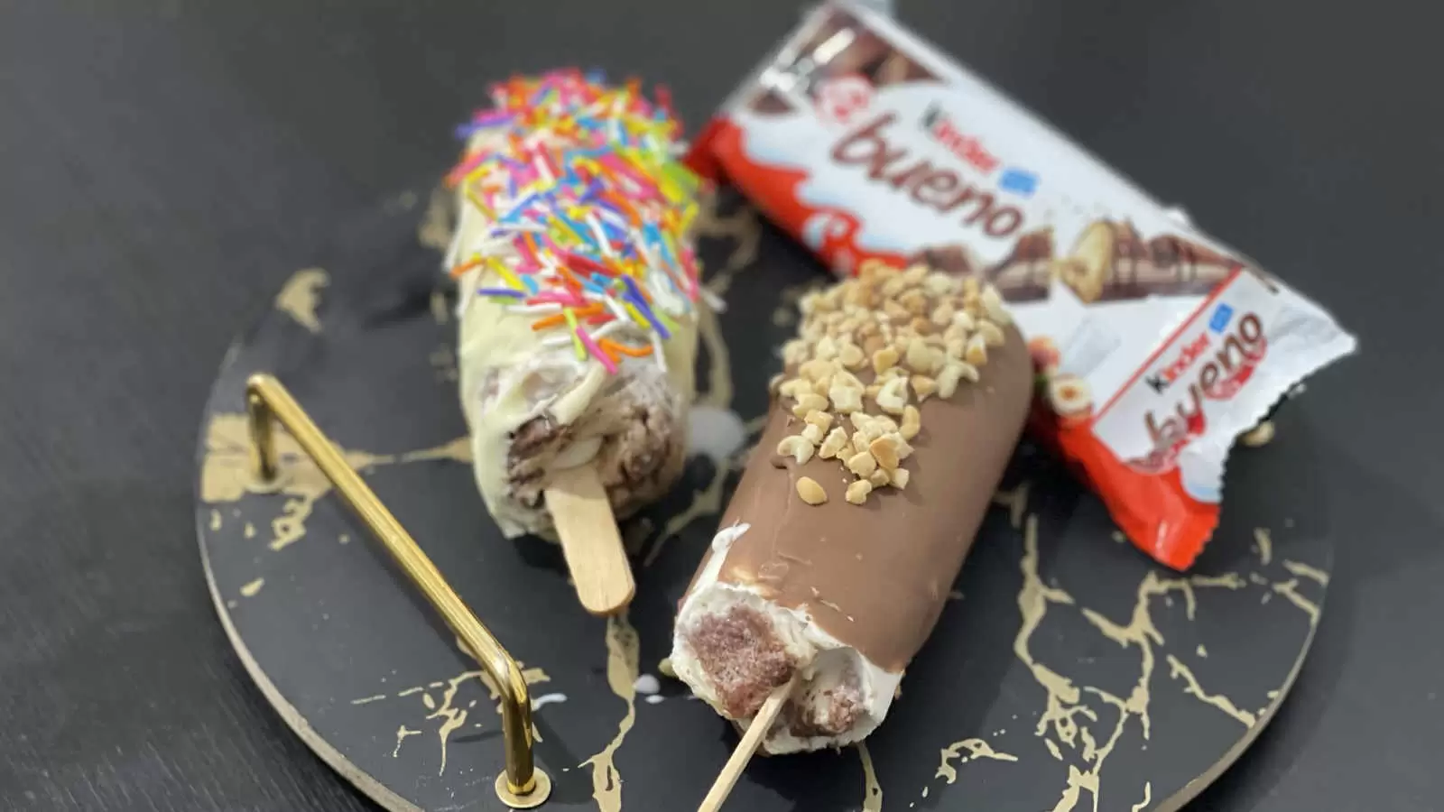 Homemade 2 Kinder Bueno ice creams on a tray a Kinder Bueno chocolate bar on a black table