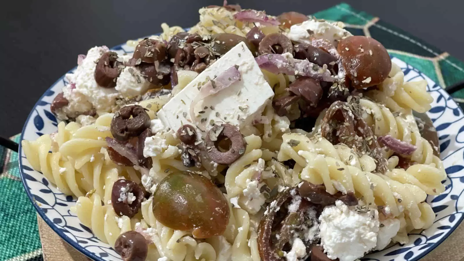 Homemade Pasta salad with Bulgarian cheese and tomatoes on a plate and a napkin underneath