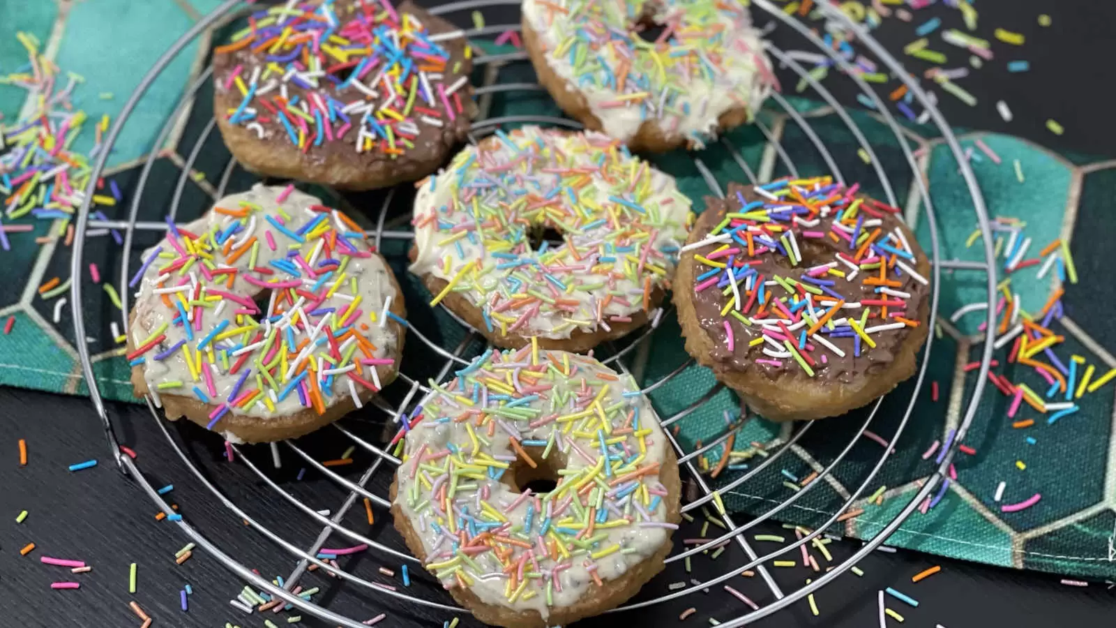 Homemade Puff pastry doughnuts on a cooling rack and a napkin underneath