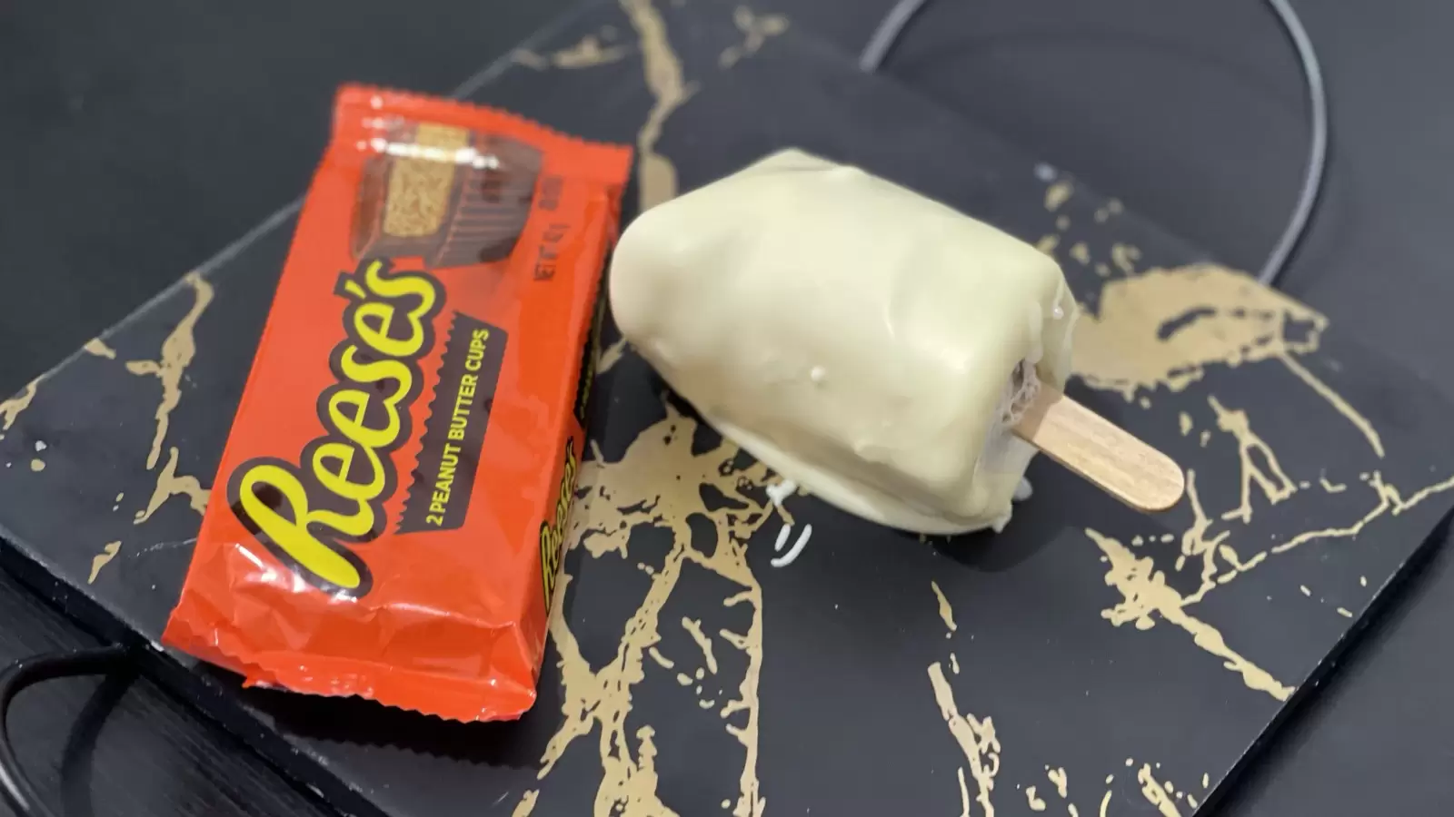 A pack of Reeses next to Homemade Reeses ice cream placed on a tray on a table