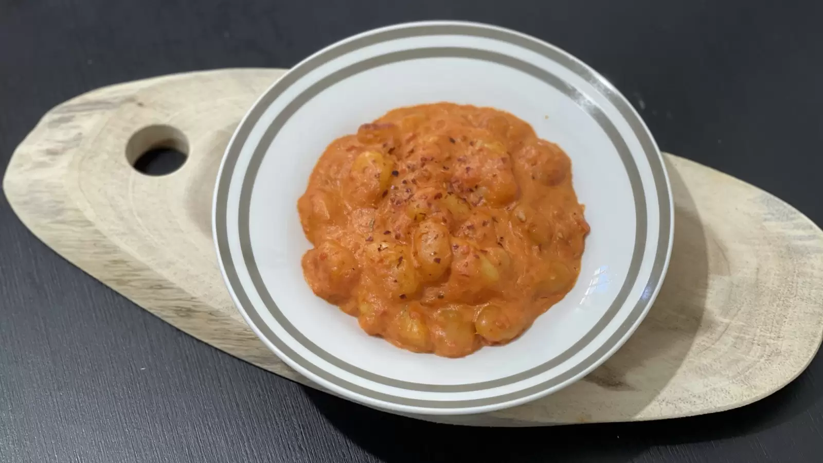 Homemade Creamy Tomato Gnocchi on a plate on a wooden board
