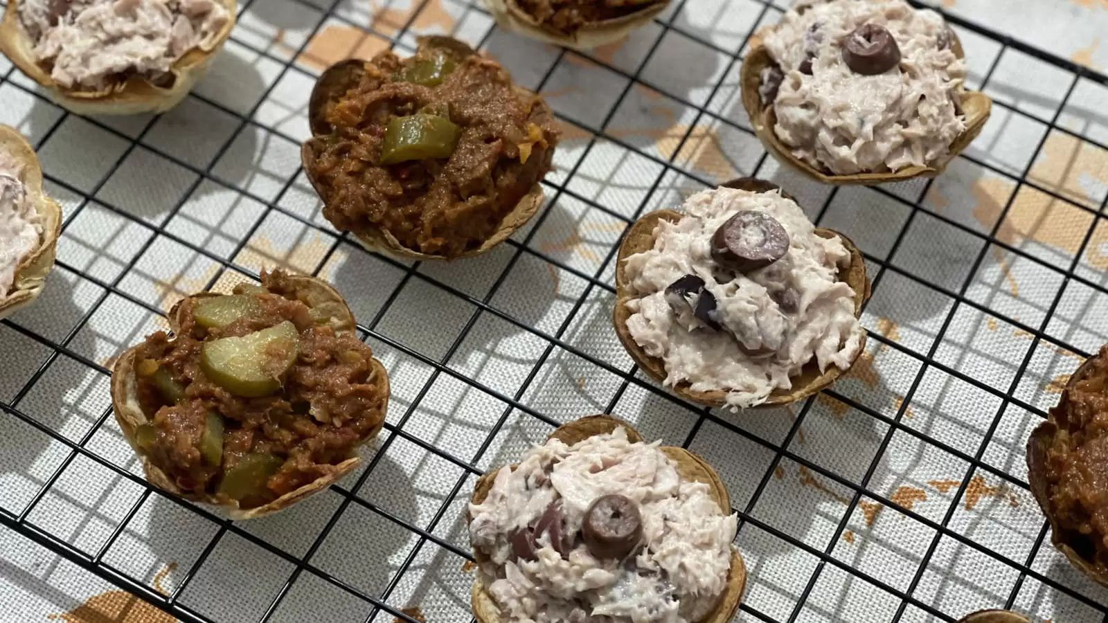 Homemade tortilla flowers filled with tuna on a cooling rack and under a napkin