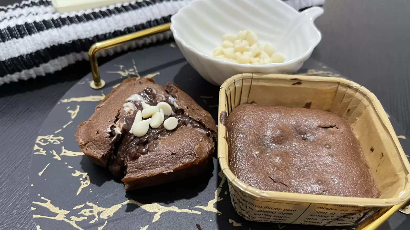 Two Nutella souffls on a tray a bowl with white chocolate and a towel on the side