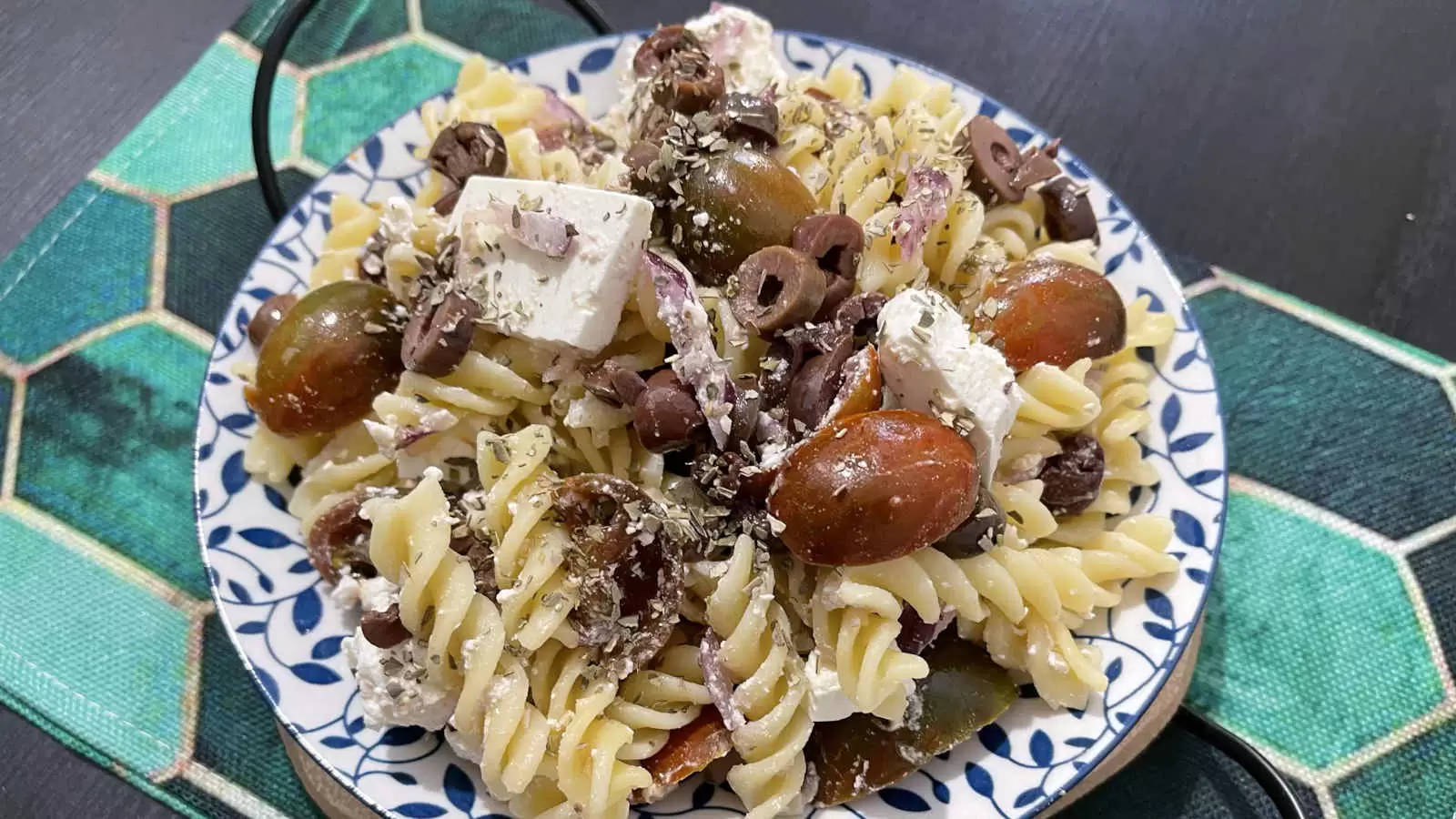 Pasta salad with Bulgarian cheese and tomatoes dish on a plate and a napkin underneath