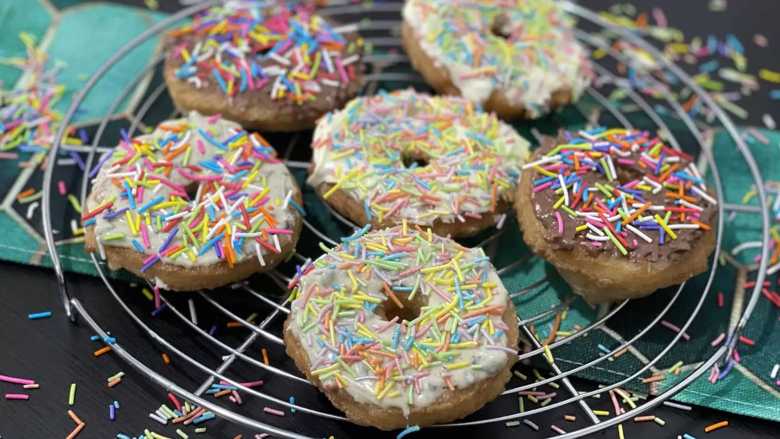 Puff pastry doughnuts on a cooling rack and a napkin underneath