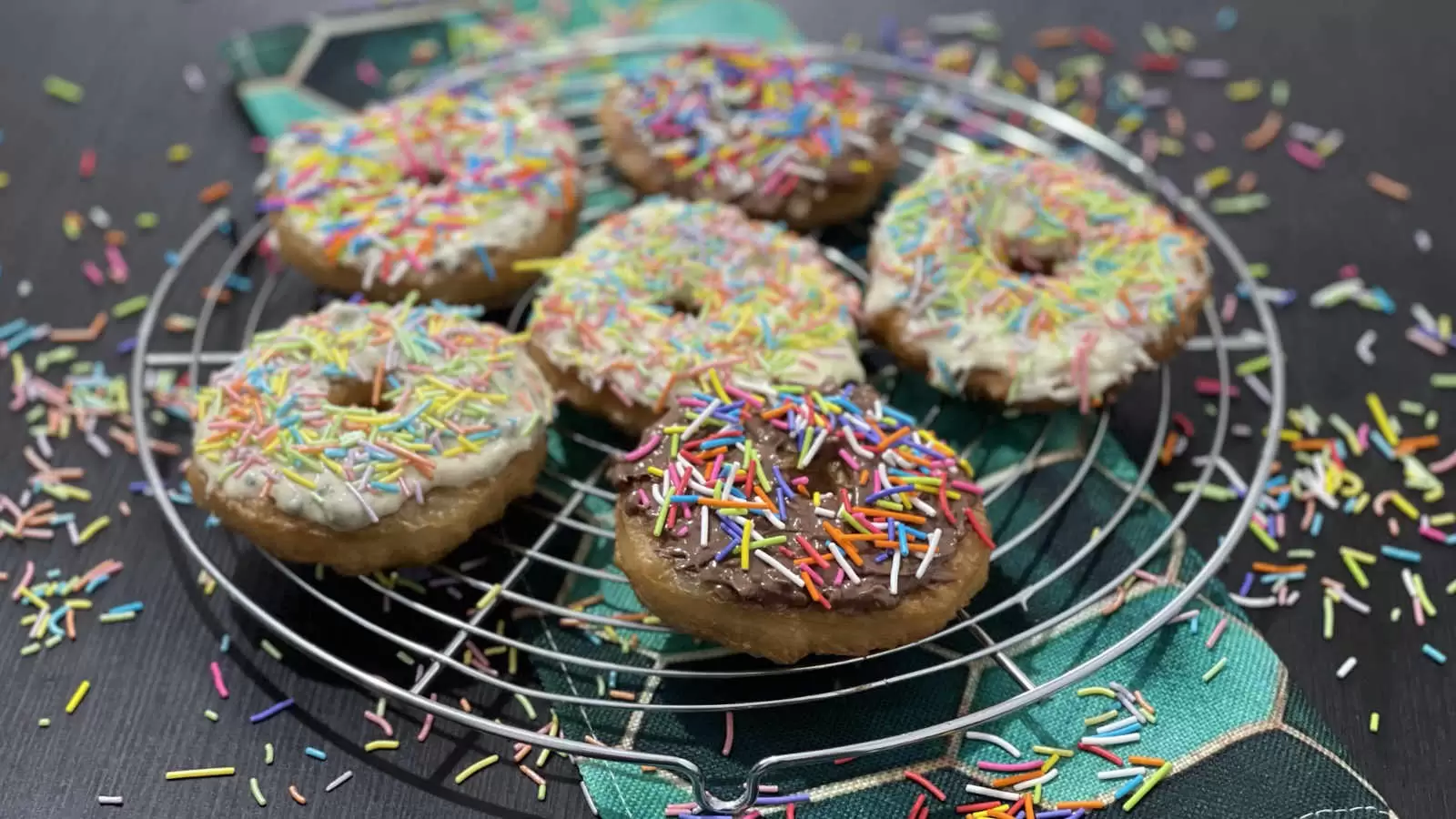 Puff pastry doughnuts dish on a cooling rack and a napkin underneath