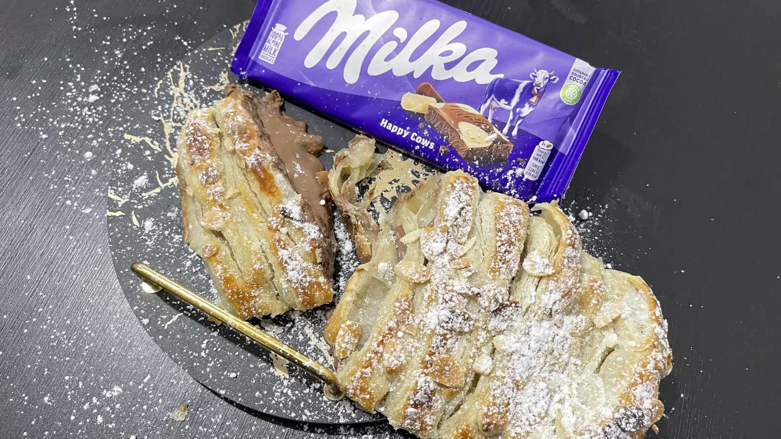 Milka chocolate bar puff pastry with Milka liquid chocolate and powdered sugar on a plate on a table