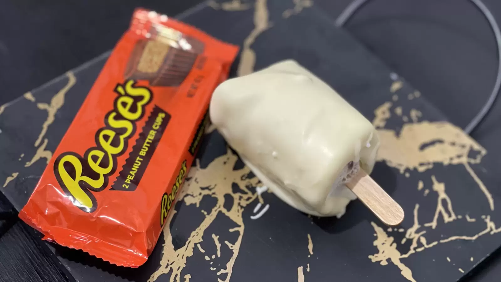 A pack of Reeses next to Reeses ice cream dessert placed on a tray on a table