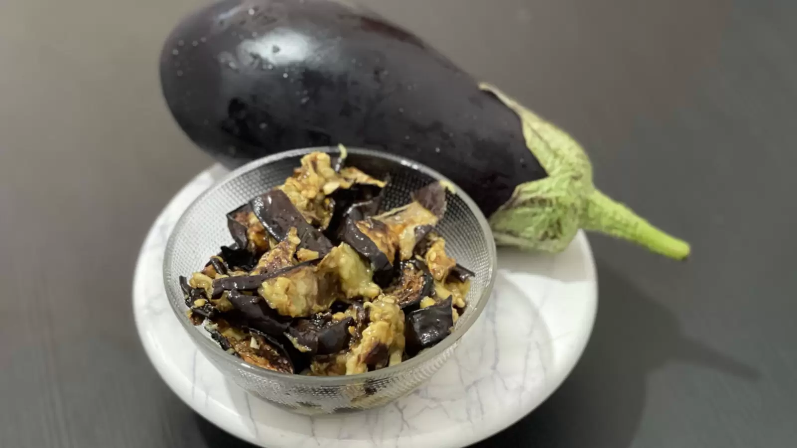 Eggplant and eggplant salad next to it in a bowl on a tray on the table