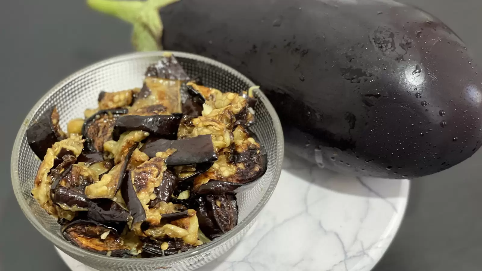 Eggplant and eggplant dish next to it in a bowl on a tray on the table