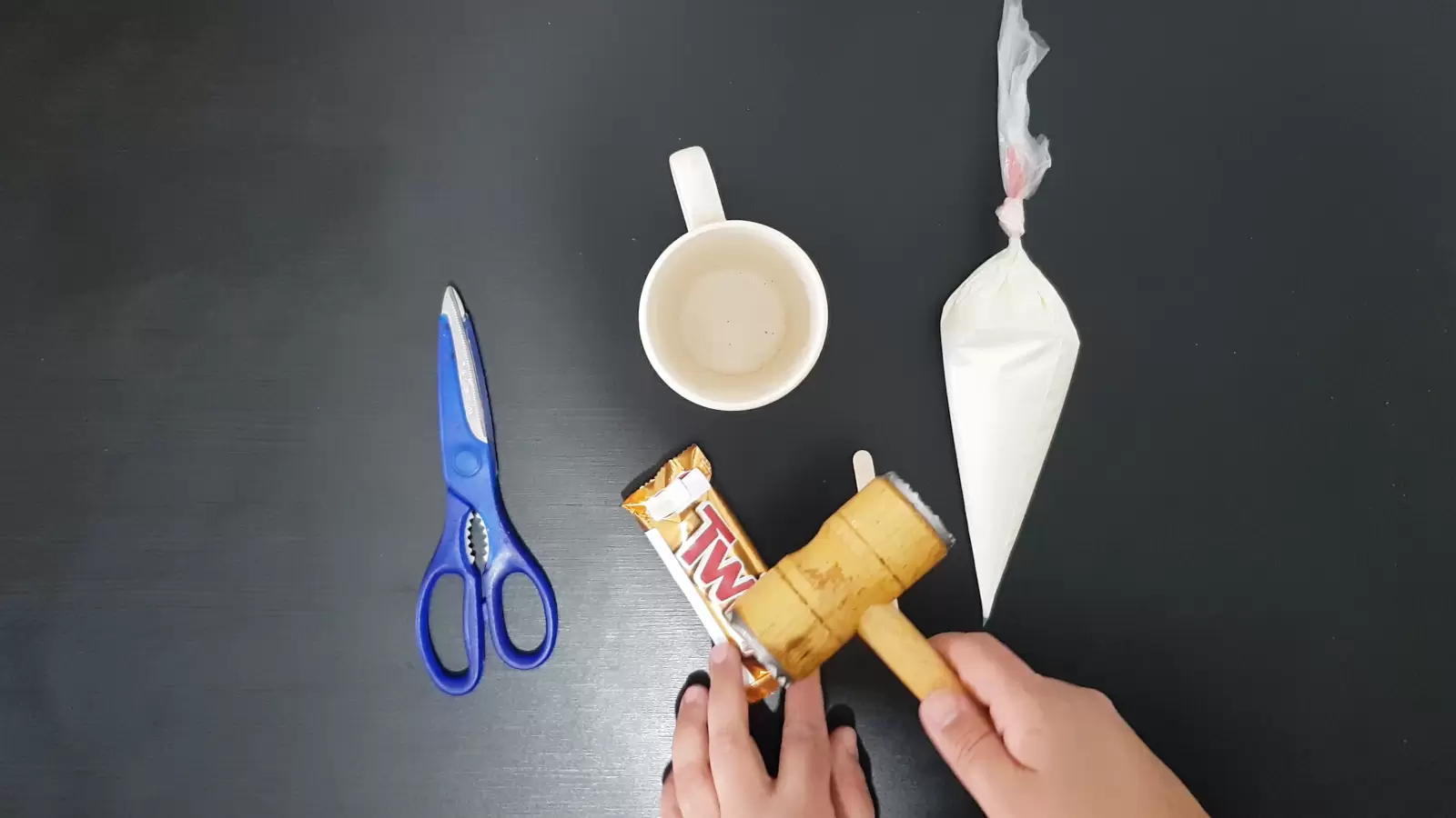 Whipped cream in a bag, mug, kitchen hammer on a Twix package, scissors