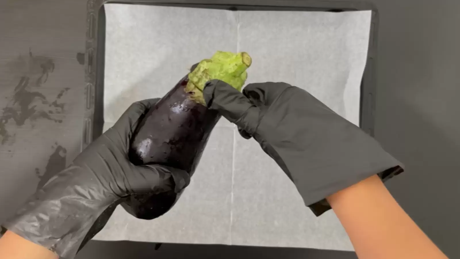 Baking sheet with baking paper, medium eggplant and knife.