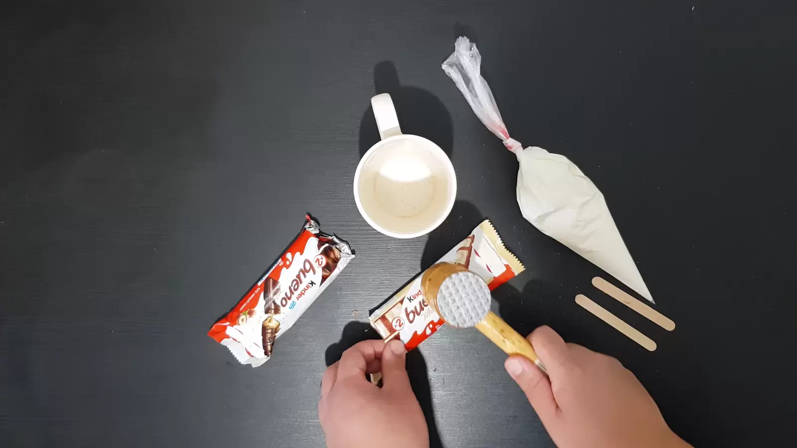 Whipped cream, a cup, Kinder Bueno, two wooden sticks, a kitchen hammer