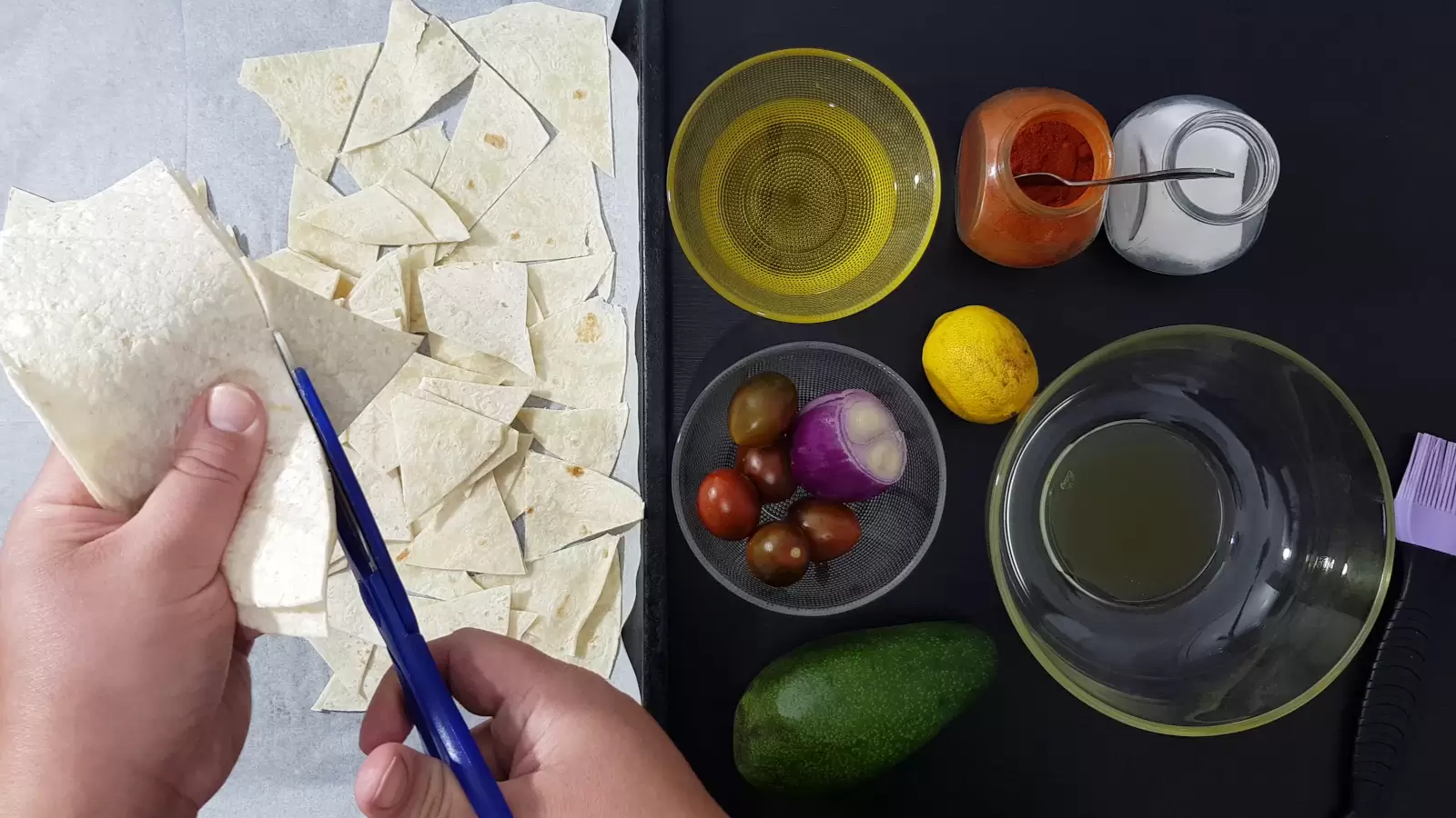 Spices, bowl with oil, empty bowl, tomatoes, purple onion, avocado, lemon, mold with tortillas and scissors