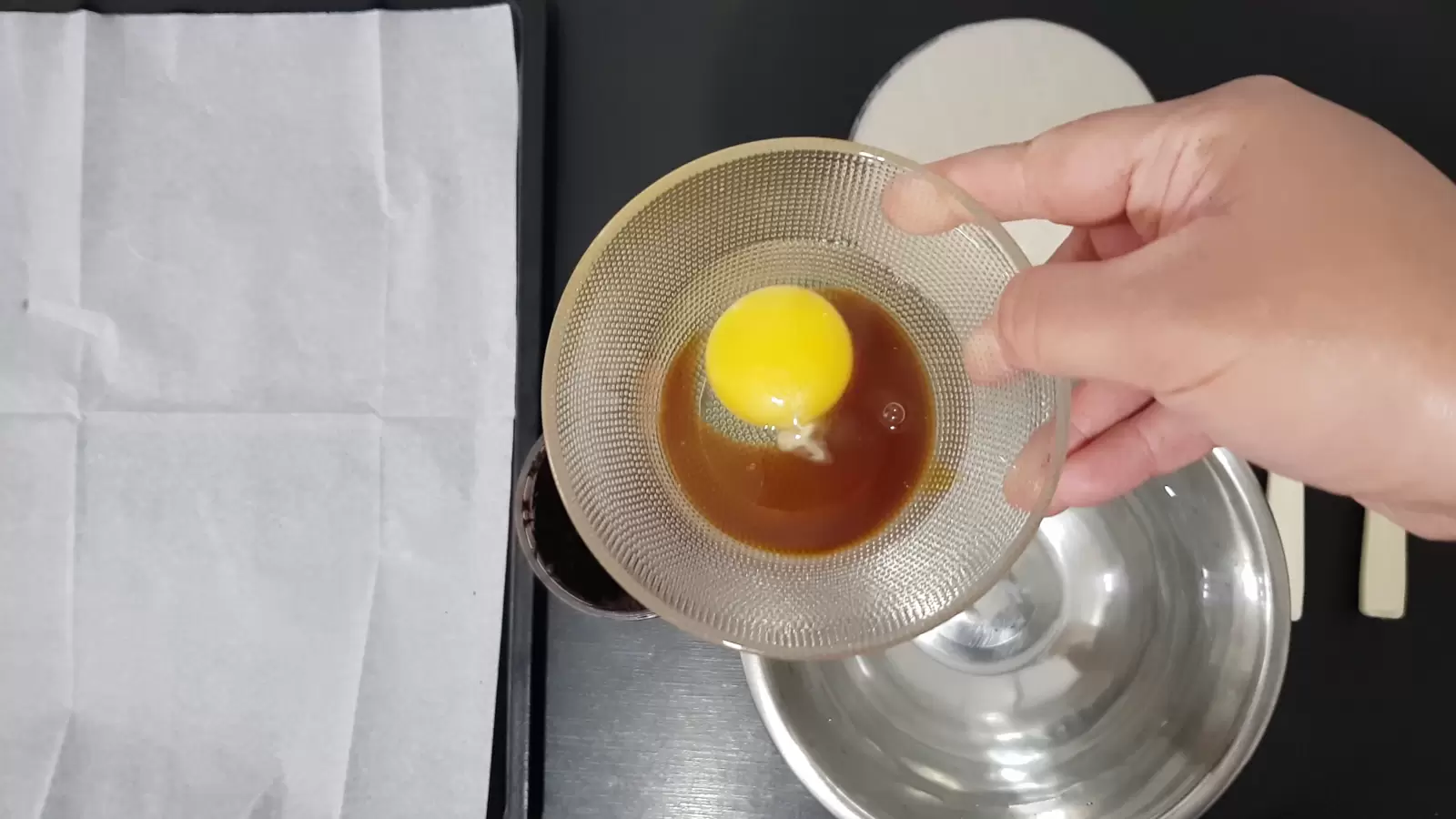 Bowl with water, bowl with egg and date honey, baking sheet with baking paper