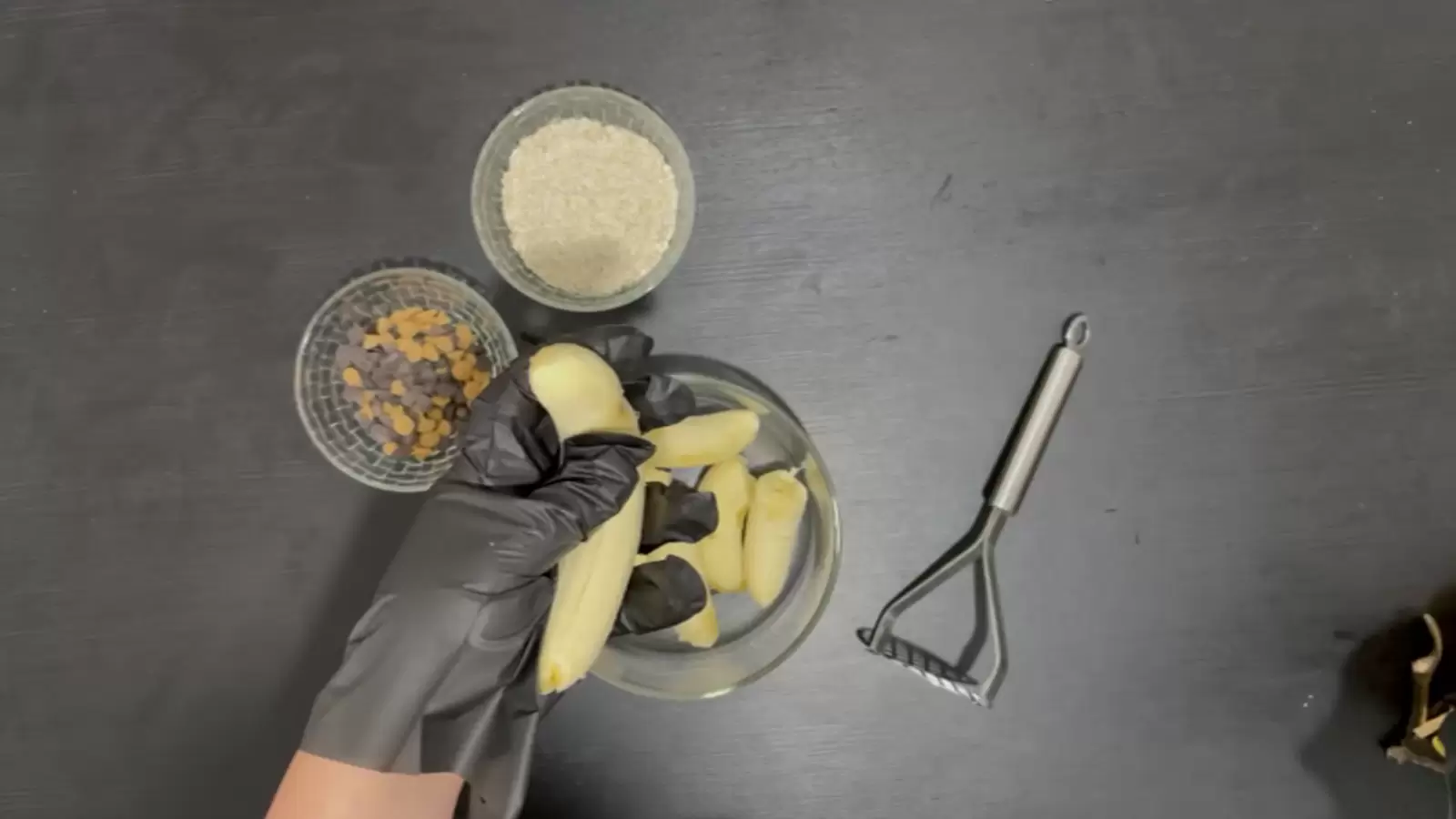potato masher, bowl of bananas, bowl of oats, bowl of chocolate chips