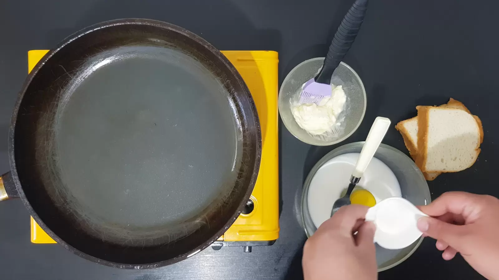 2 slices of bread, bowl with butter and brush for brushing, bowl with egg milk and sugar and fork, frying pan