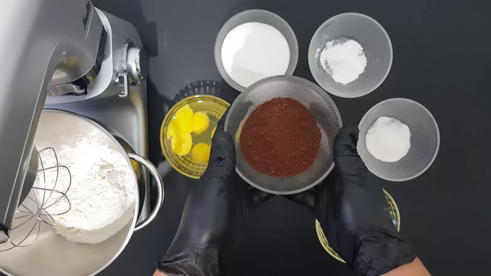 Bowl with baking powder, bowl with vanilla sugar, bowl with sugar, bowl with eggs, bowl with cocoa, mixer with bowl and flour