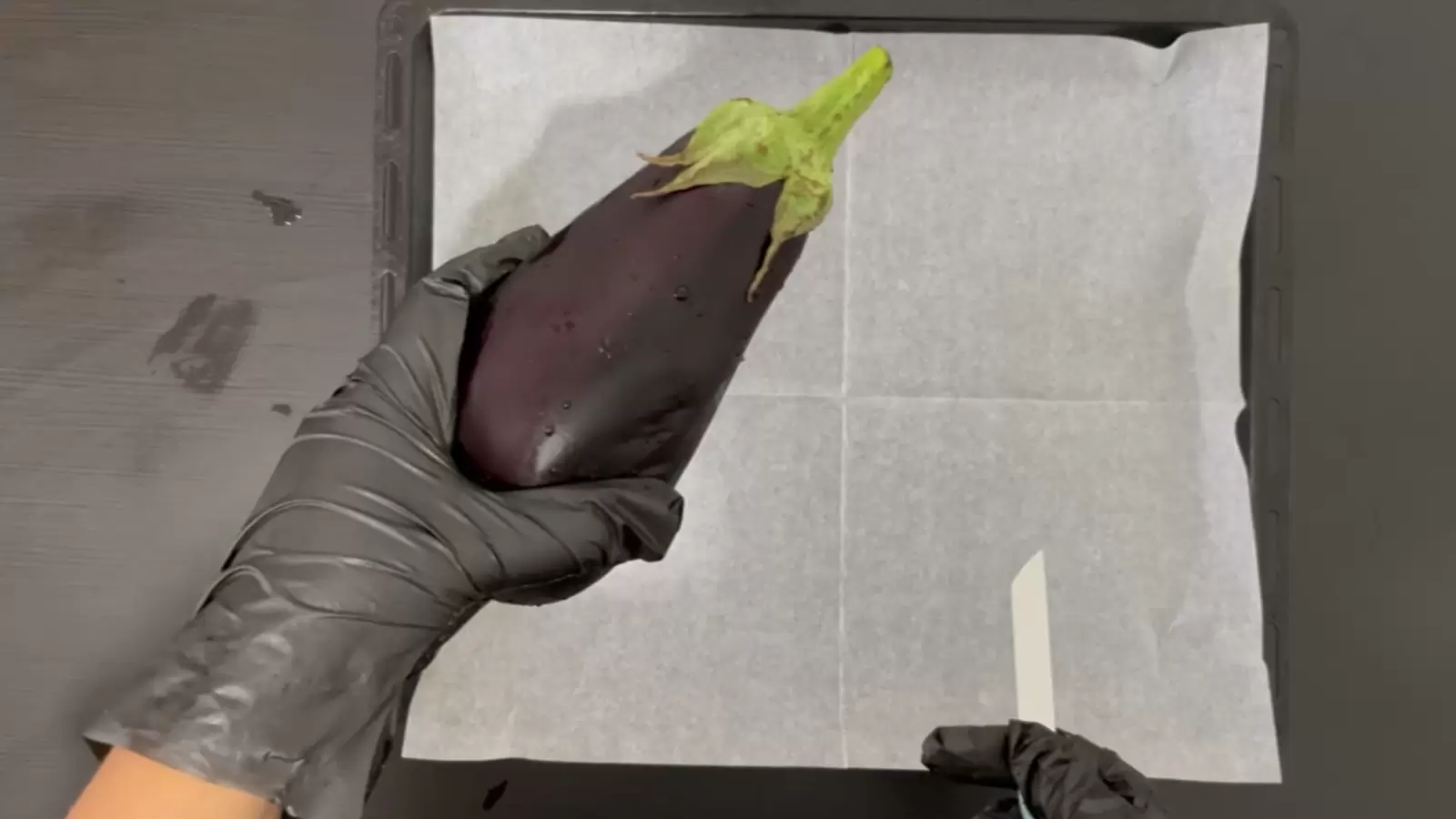 Oven tray with baking paper, eggplant, knife