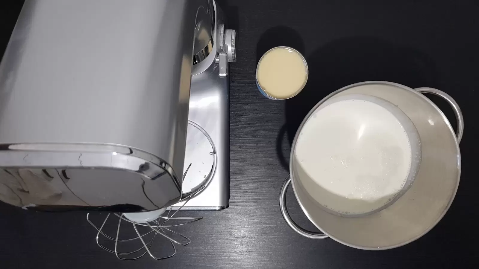 A bowl with whipping cream, a can of condensed milk, a mixer