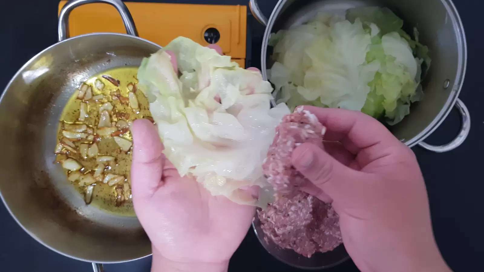 Pot with cabbage leaves, meat filling, pot with sauce and onions