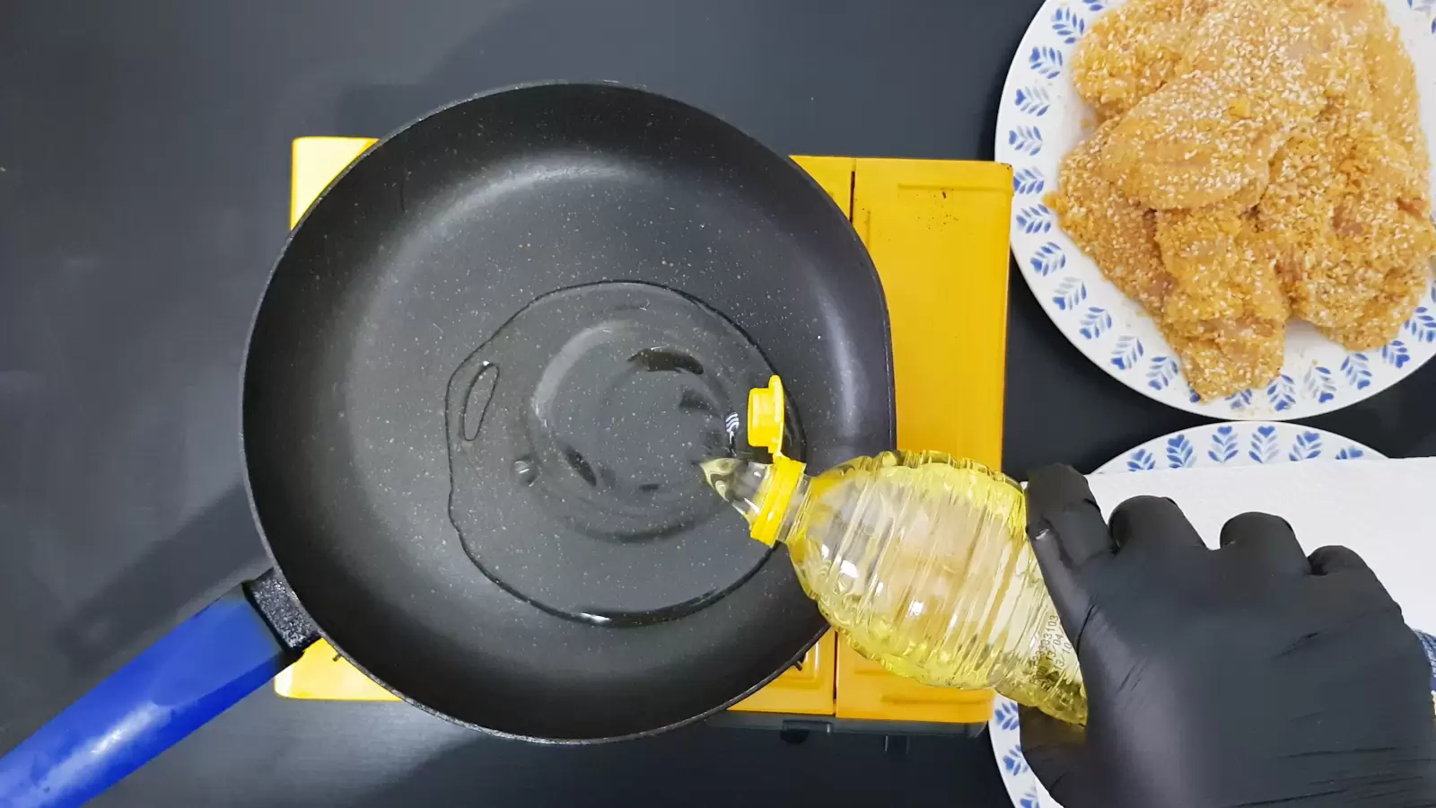 A plate with schnitzels, a pan with oil, a bottle of oil