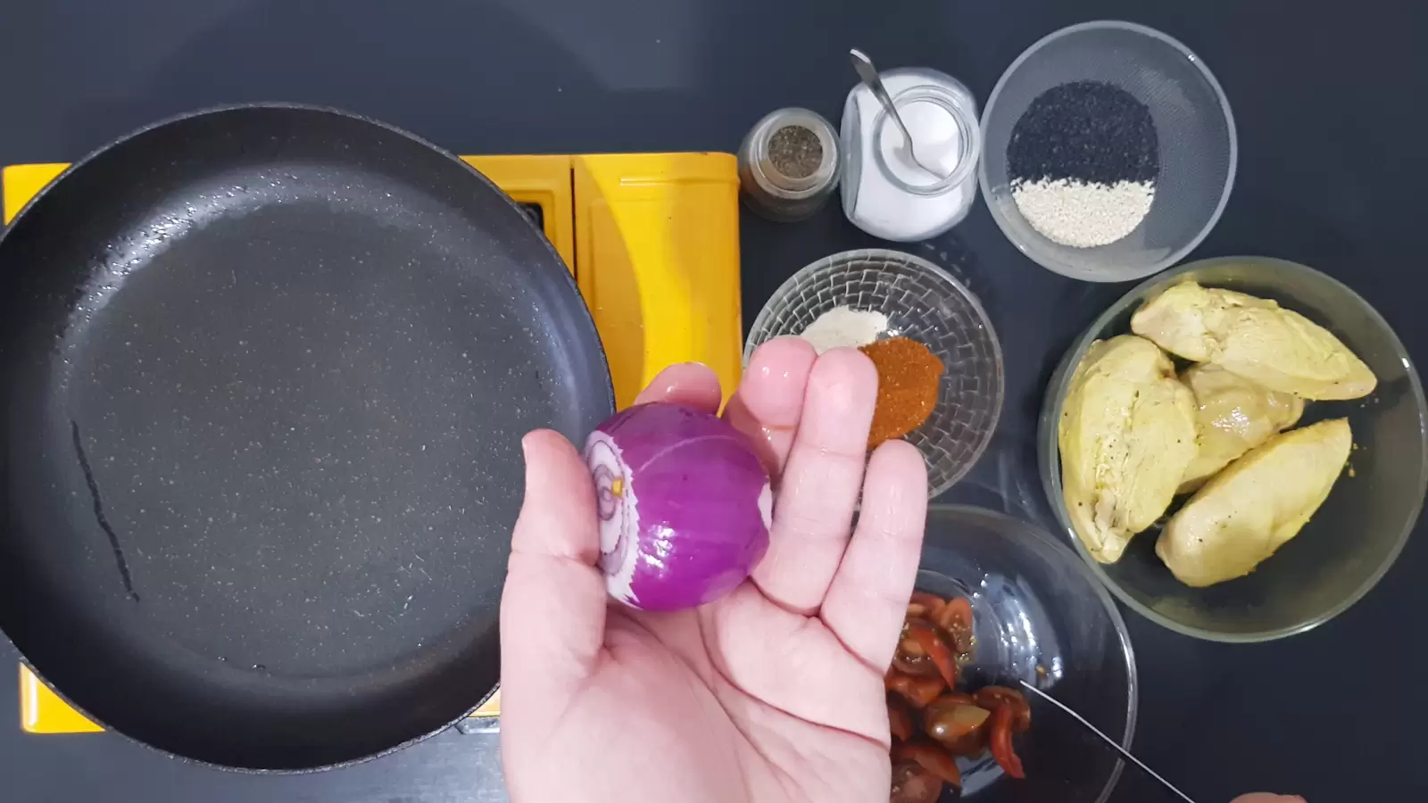 Spices, boiled chicken, sesame, pan, tomatoes, purple onion and a knife