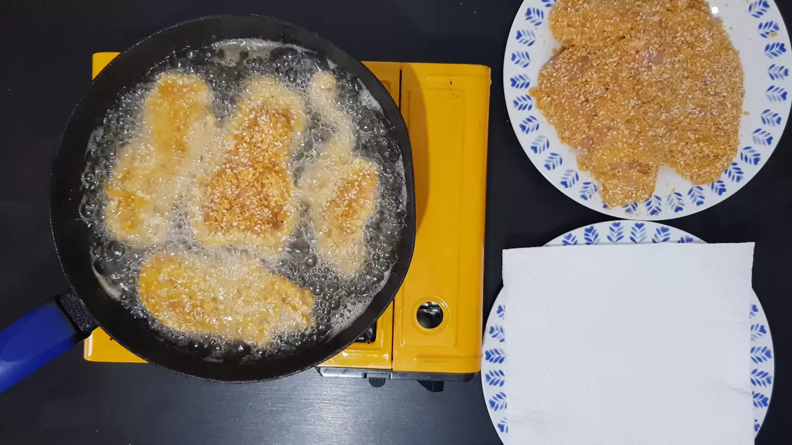 Plate with schnitzel, pan with oil and schnitzel, plate with absorbent paper