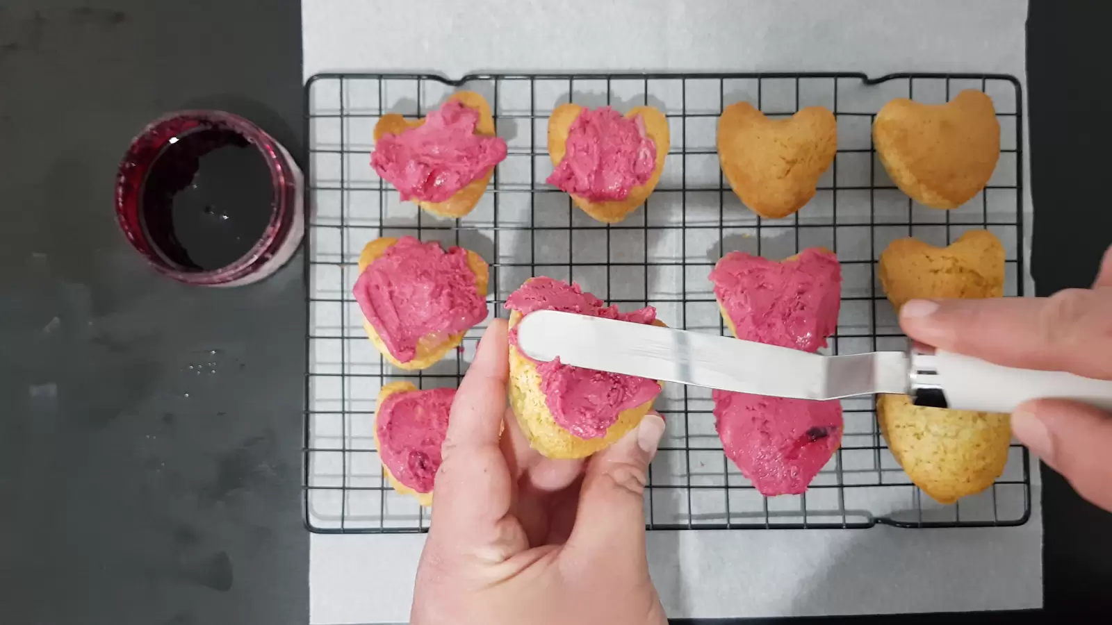 Vanilla cupcakes, spatula, cooling rack, baking paper, bowl with berries