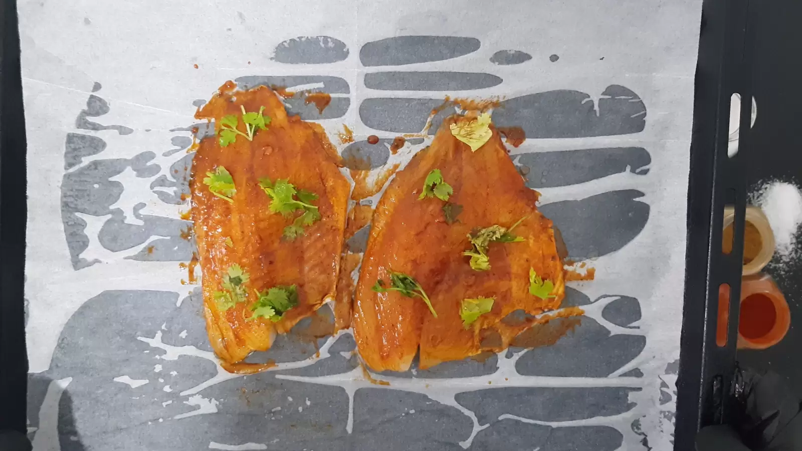 2 tilapia fish in an oven dish, marinated with coriander