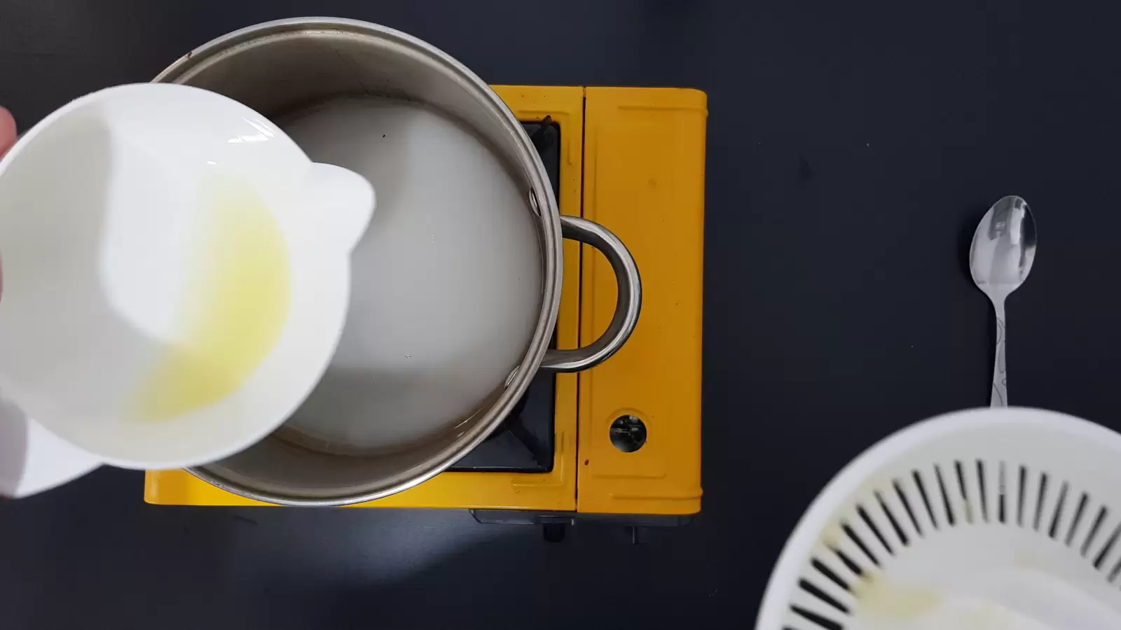 Juicer with lemon juice, spoon, pot with water, bowl with sugar