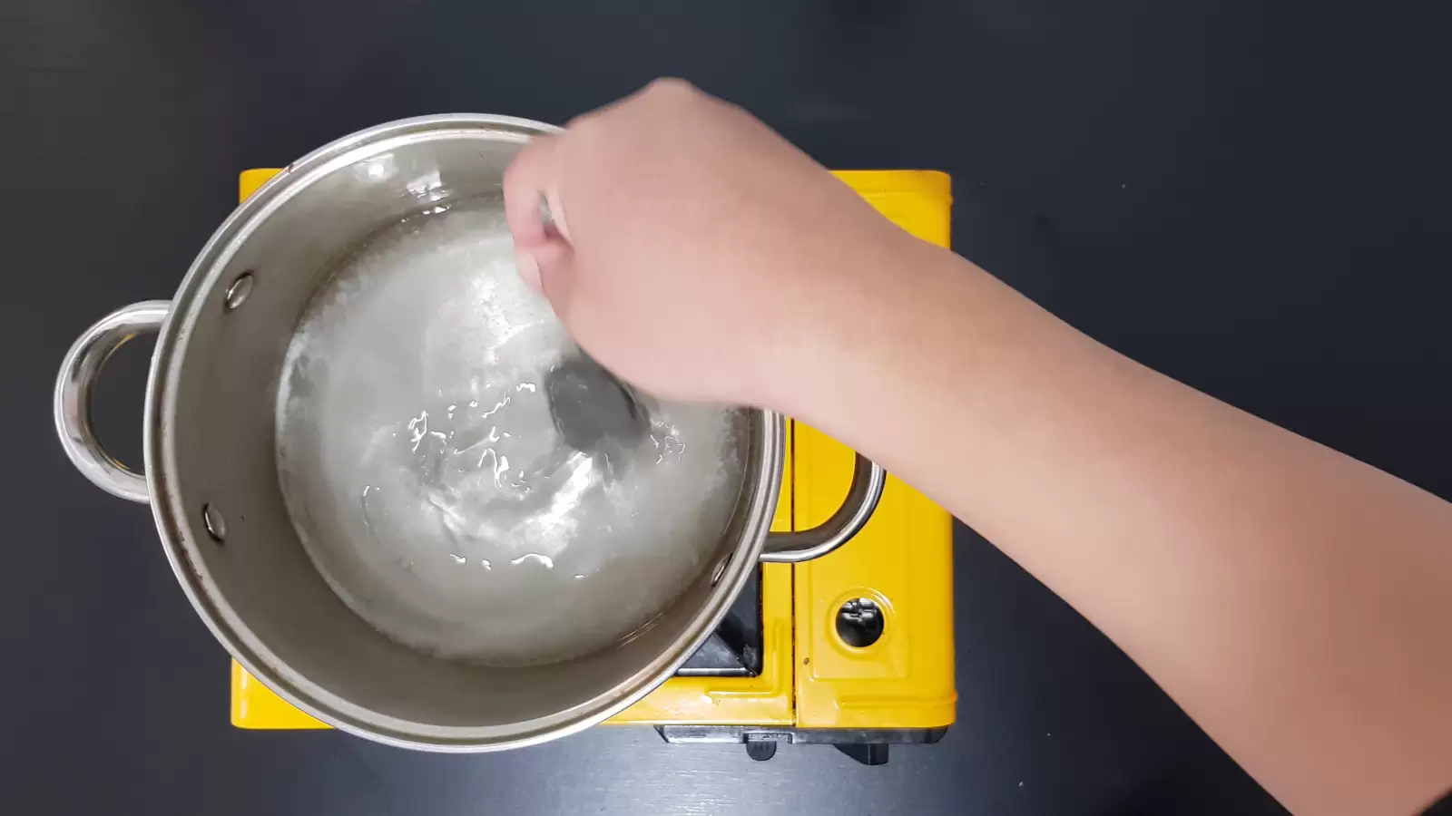 A pot with sugar sauce and a spoon