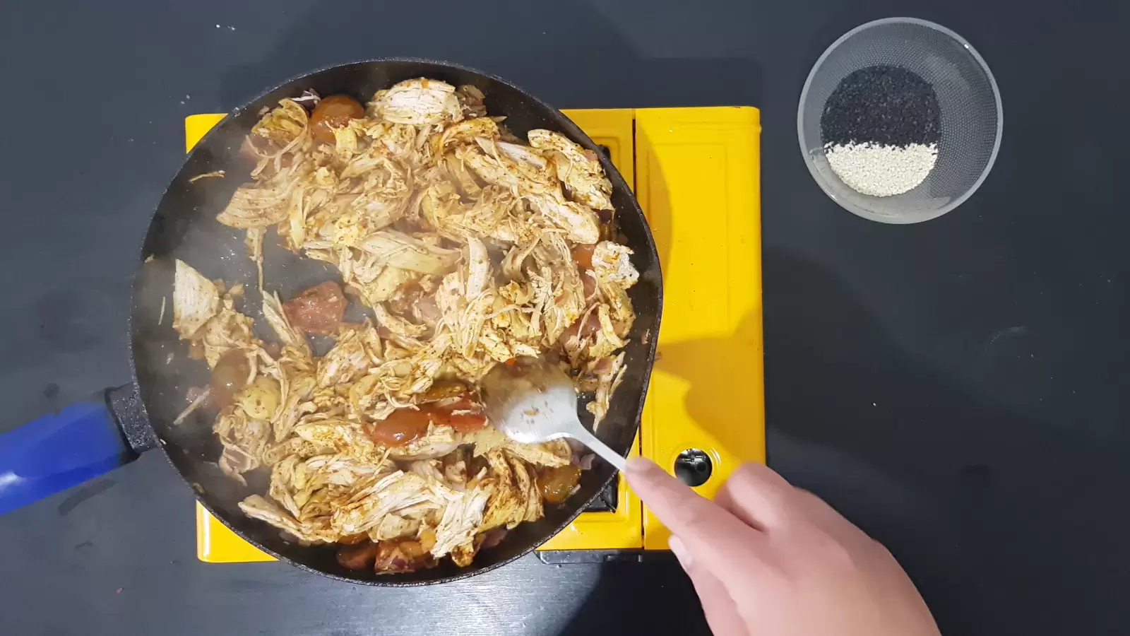 Pan with chicken, tomatoes and onions, bowl with sesame