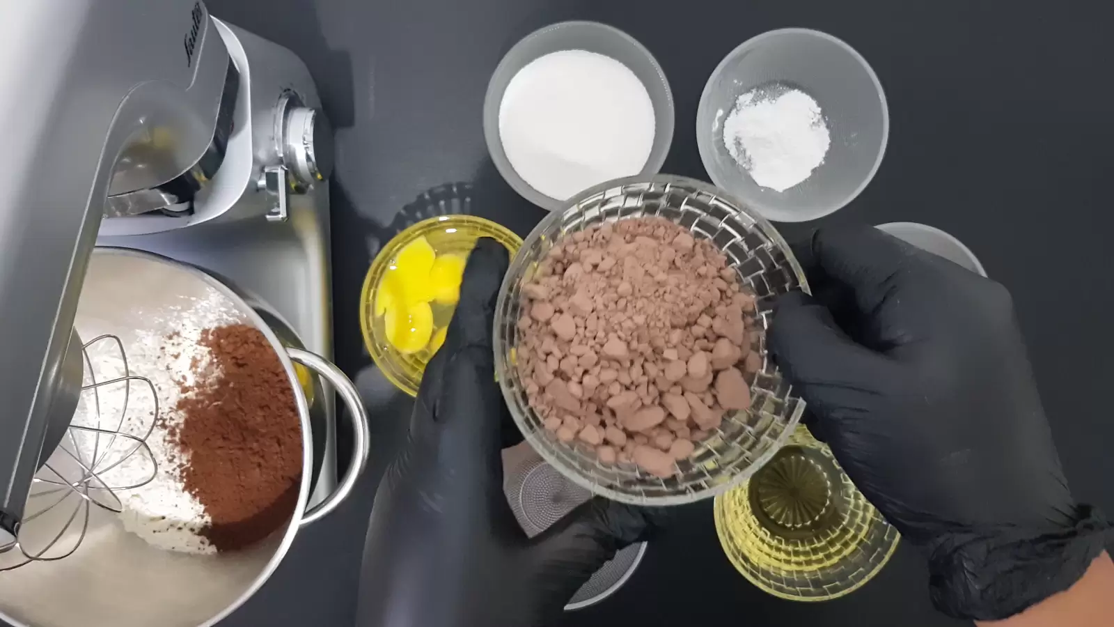 Bowl with baking powder, bowl with vanilla sugar, bowl with sugar, bowl with eggs, bowl with chocolate powder, mixer with bowl and flour, bowl with oil