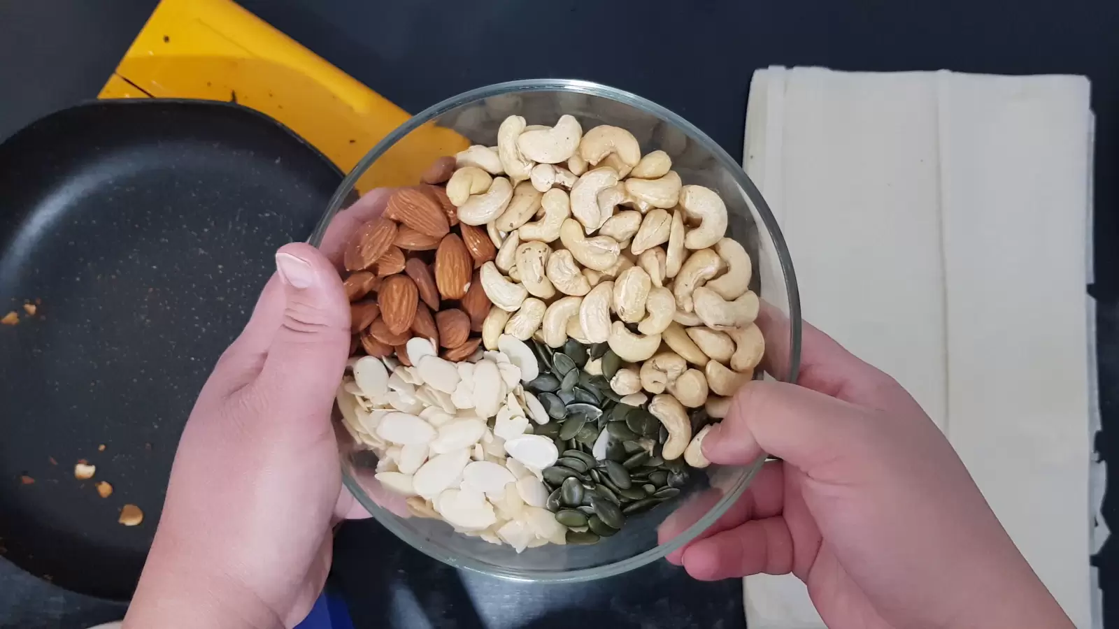 Filo sheets on a table, an assortment of nuts in a bowl, a pan with walnuts